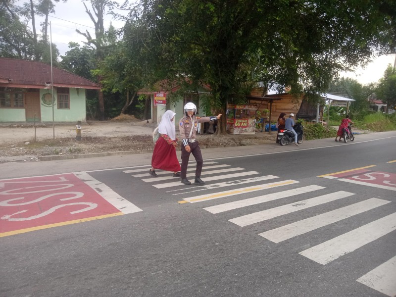 Polisi Lakukan Pengaturan Arus Lalu Lintas dan Menyeberangkan Anak Sekolah di KM 25 SDN 007